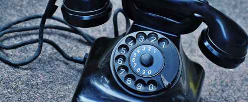 black rotary telephone at top of gray surface